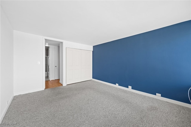 unfurnished bedroom featuring baseboards, carpet, and a closet
