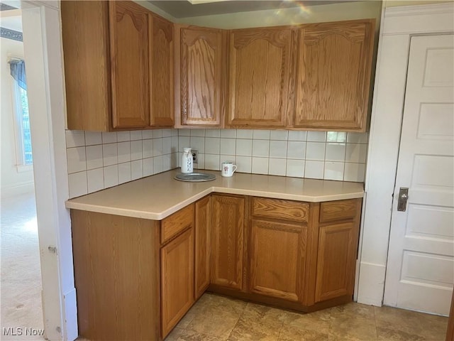 kitchen with light countertops, brown cabinets, and decorative backsplash