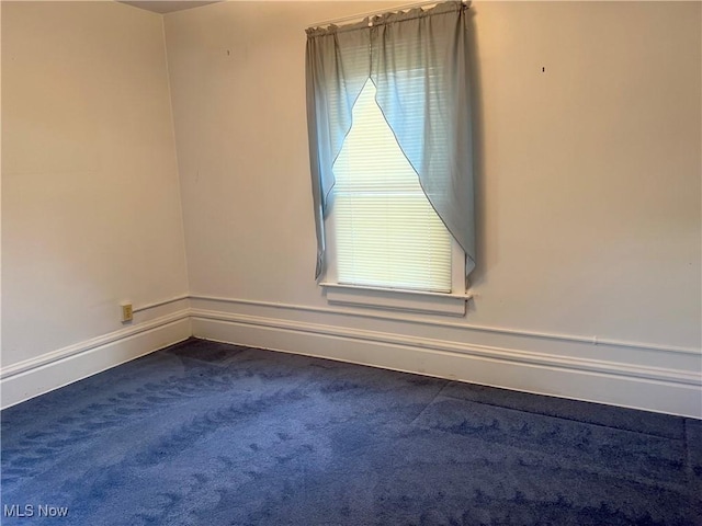 carpeted spare room featuring baseboards