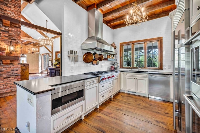 kitchen with exhaust hood, stainless steel appliances, an inviting chandelier, and beam ceiling