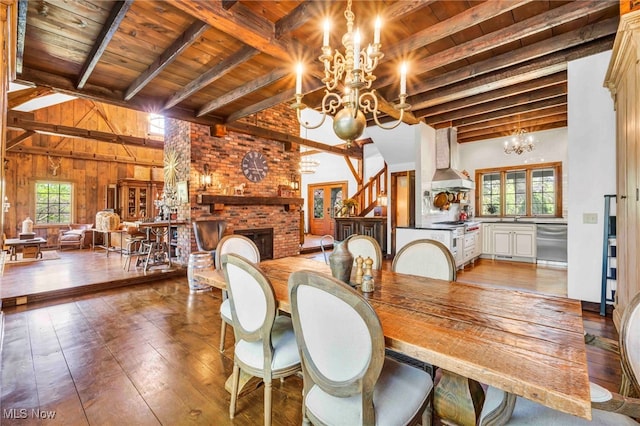 dining area with wood-type flooring, a brick fireplace, beamed ceiling, a chandelier, and wooden ceiling