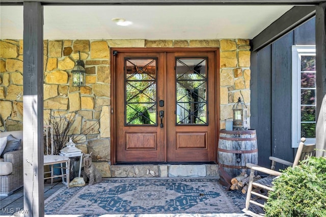 view of exterior entry featuring french doors and stone siding