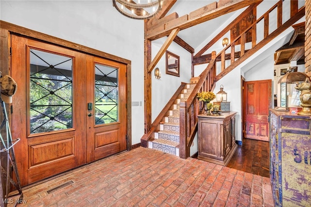 entrance foyer featuring stairs, high vaulted ceiling, visible vents, and brick floor