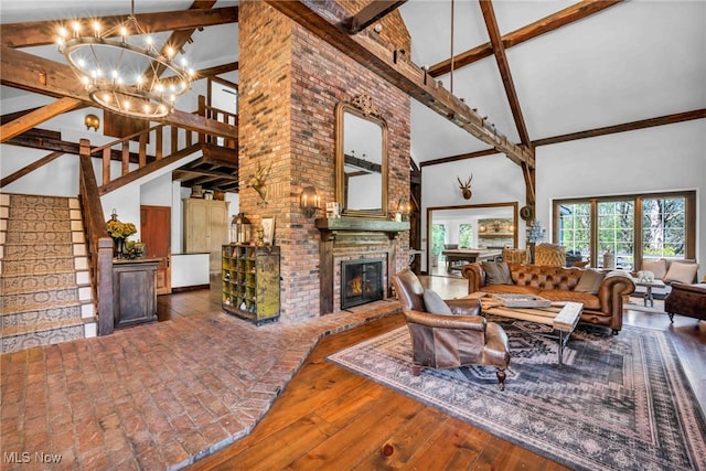 living room featuring beam ceiling, a brick fireplace, high vaulted ceiling, a chandelier, and stairway