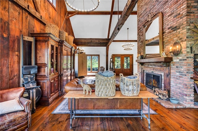 living room featuring an inviting chandelier, a fireplace, high vaulted ceiling, beamed ceiling, and hardwood / wood-style flooring