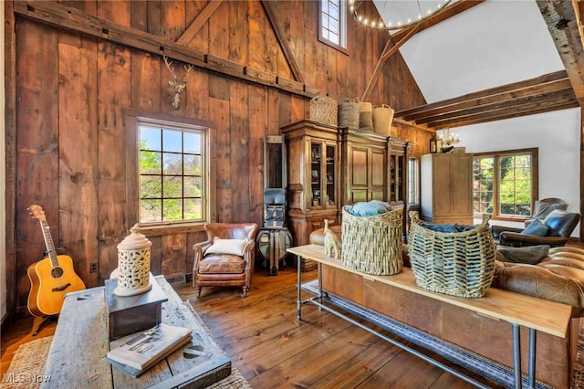 sitting room featuring wood-type flooring, high vaulted ceiling, and wood walls