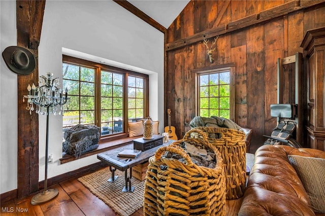 living area featuring wooden walls, high vaulted ceiling, baseboards, and wood-type flooring