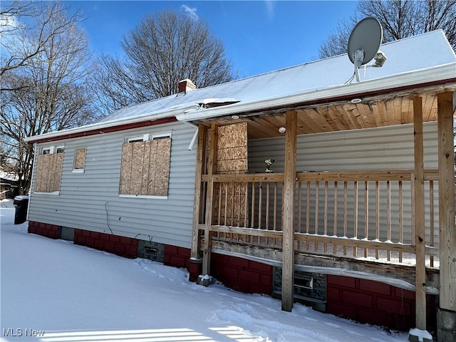 snow covered property with a chimney and crawl space