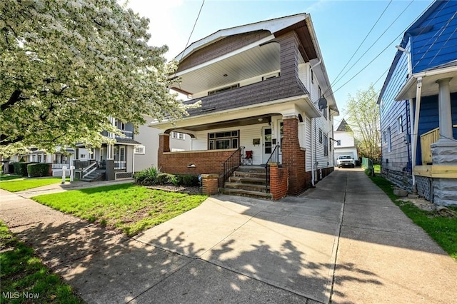 view of front of property with covered porch, brick siding, a shingled roof, and a detached garage