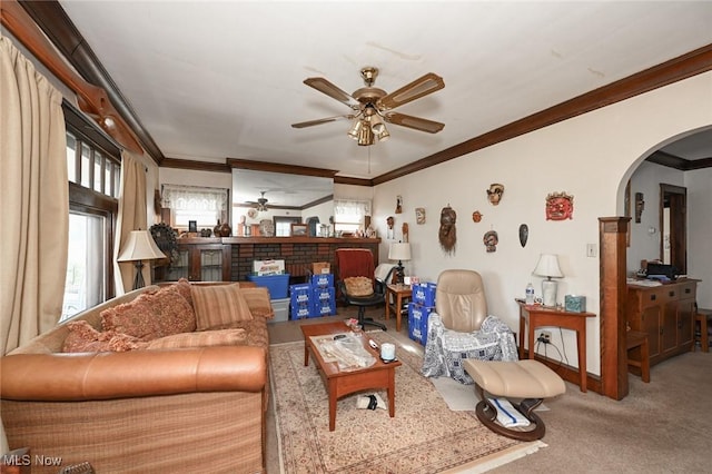 carpeted living room with arched walkways, ceiling fan, and ornamental molding