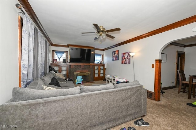 living room featuring crown molding, arched walkways, a ceiling fan, and a fireplace