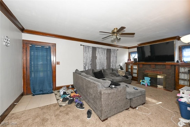 carpeted living area with a ceiling fan, crown molding, a fireplace, baseboards, and tile patterned floors
