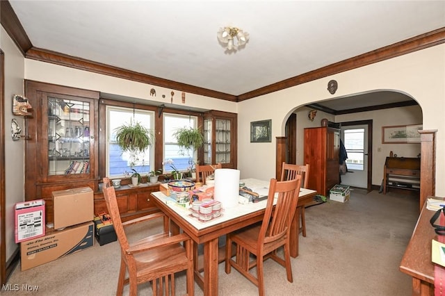 dining room featuring crown molding, arched walkways, and light colored carpet
