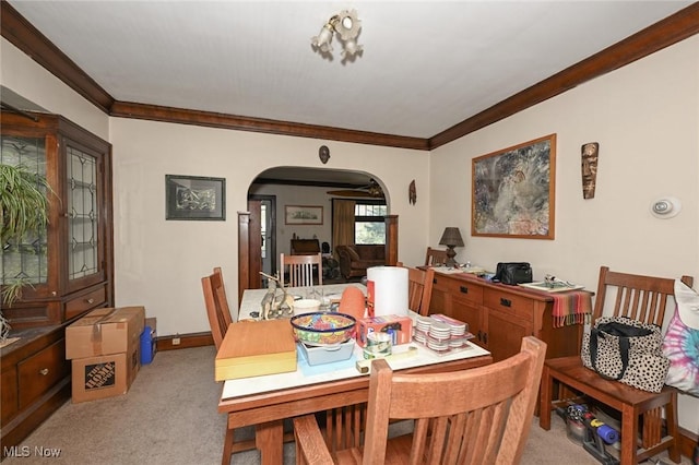 dining space with crown molding, arched walkways, baseboards, and light carpet