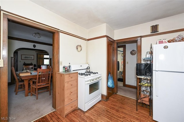 kitchen featuring white appliances, arched walkways, and light wood-type flooring