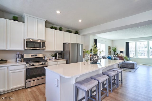 1662 N Eckert Ln, Akron, OH 44313 - kitchen featuring light wood-style flooring, a center island, a breakfast bar, open floor plan, and appliances with stainless steel finishes