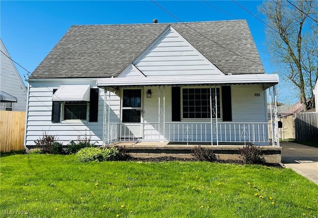 bungalow-style home featuring roof with shingles, fence, covered porch, and a front yard