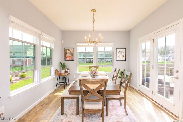 dining area featuring an inviting chandelier, baseboards, and light wood finished floors