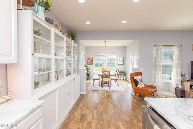 kitchen featuring white cabinetry, a chandelier, a healthy amount of sunlight, and light wood-style floors