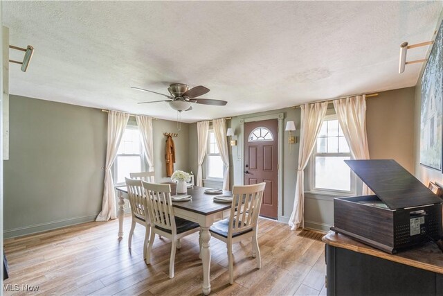 dining room with baseboards, light wood-style flooring, a ceiling fan, and a textured ceiling
