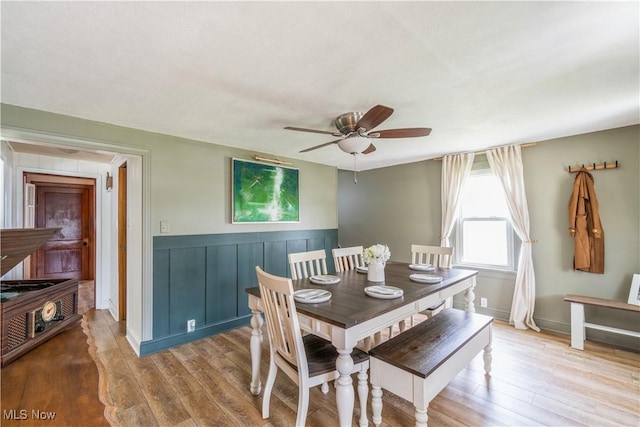 dining room with wainscoting, a ceiling fan, and wood finished floors