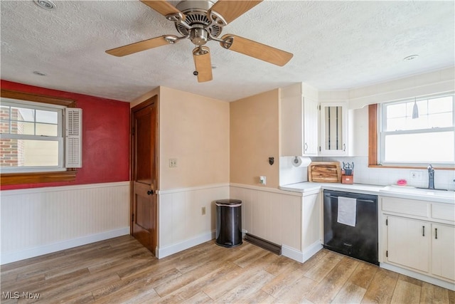 kitchen with a textured ceiling, a sink, light wood finished floors, and dishwasher