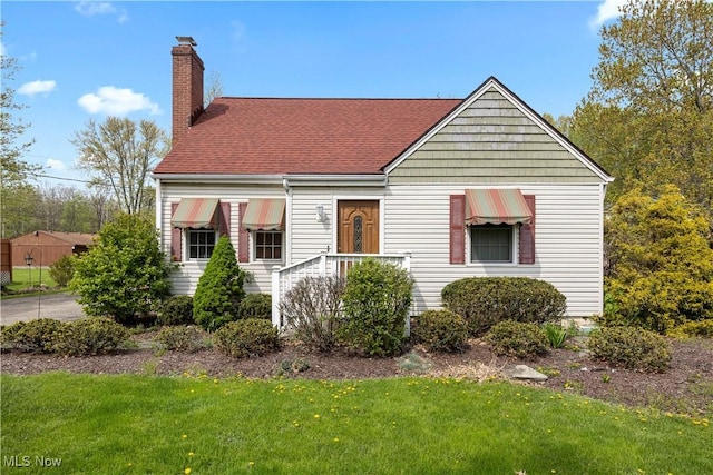 bungalow featuring a shingled roof, a front lawn, and a chimney