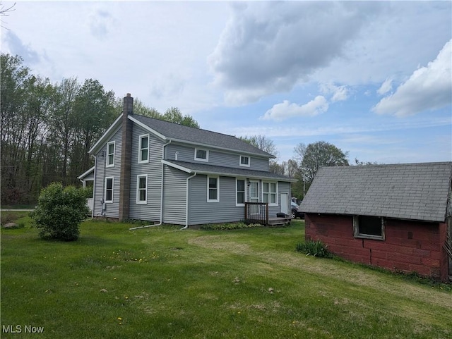 back of house featuring a yard and a chimney