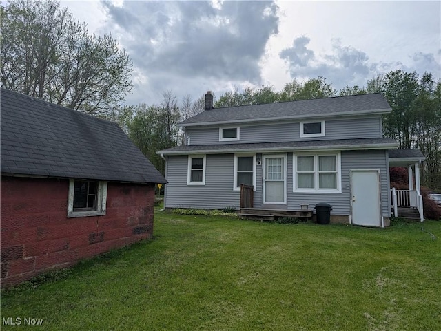 rear view of house featuring a lawn, a shingled roof, and a chimney