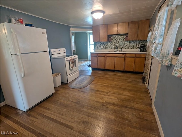 kitchen featuring a sink, brown cabinets, dark wood-style flooring, and white appliances