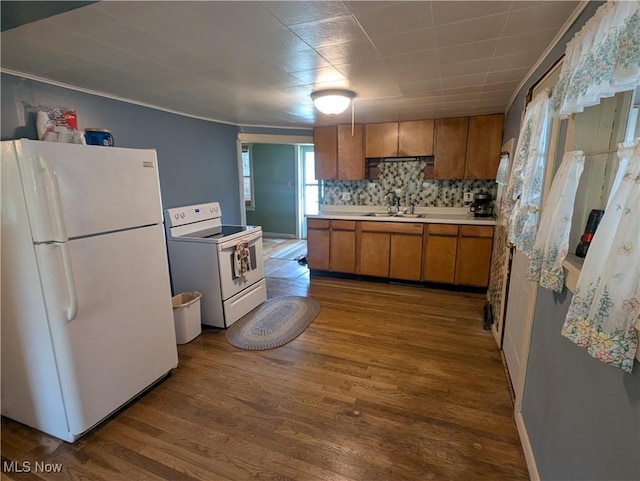 kitchen with dark wood-style flooring, brown cabinets, a sink, light countertops, and white appliances