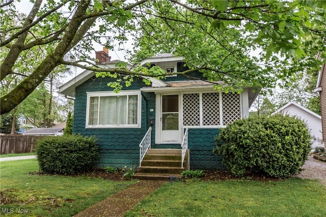 bungalow-style home featuring fence, a front yard, a chimney, and entry steps