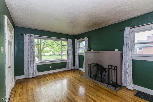 unfurnished living room featuring a textured ceiling, visible vents, and hardwood / wood-style floors