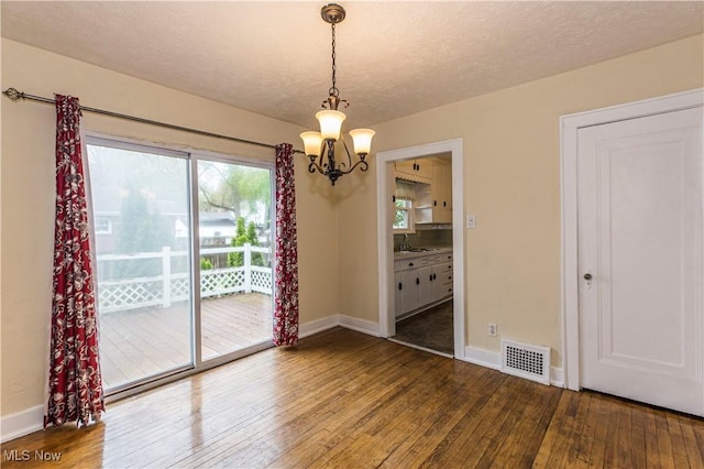 unfurnished dining area featuring visible vents, a sink, baseboards, wood-type flooring, and a chandelier