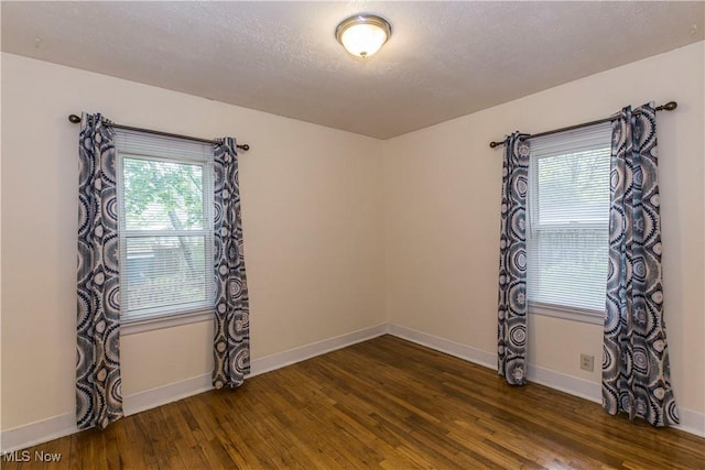 spare room featuring baseboards and dark wood finished floors