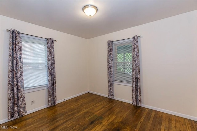 spare room featuring baseboards and hardwood / wood-style floors