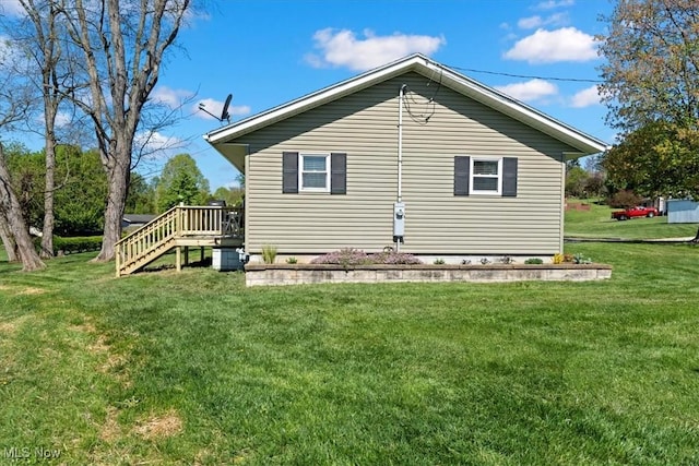 view of side of property featuring a lawn, a wooden deck, and stairs