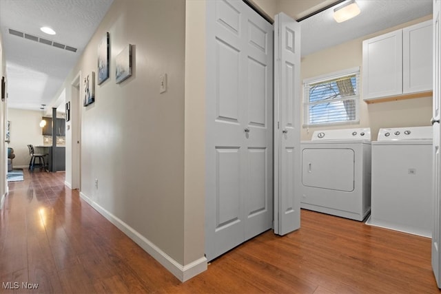 washroom with visible vents, light wood finished floors, independent washer and dryer, and cabinet space