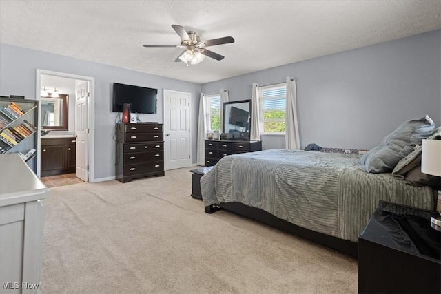bedroom with baseboards, a ceiling fan, connected bathroom, and light carpet