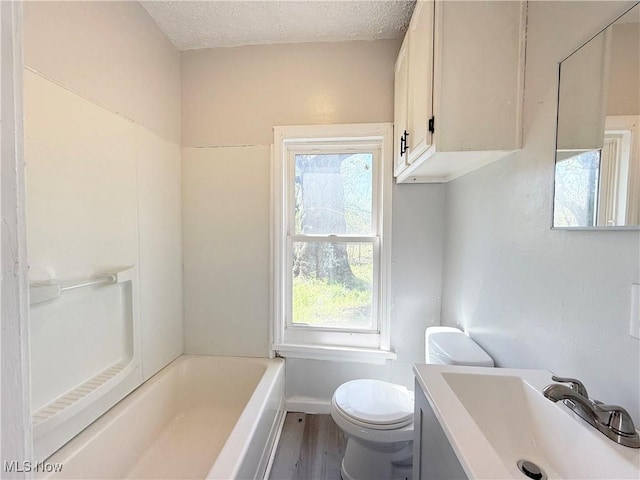 full bath featuring vanity, wood finished floors, toilet, a bathtub, and a textured ceiling