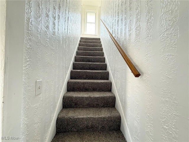 stairway with carpet floors and a textured wall