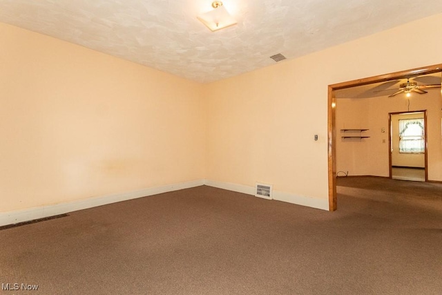 unfurnished room featuring visible vents, a ceiling fan, baseboards, and dark carpet