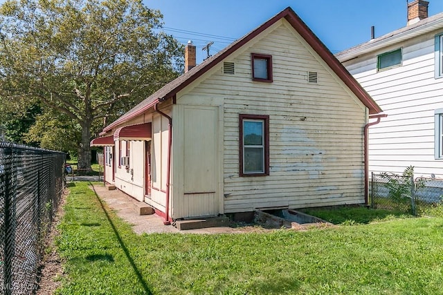 rear view of property with a fenced backyard, a chimney, and a yard