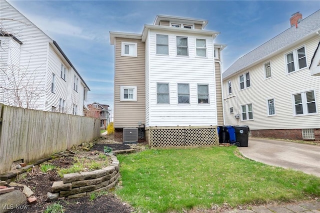 rear view of house featuring a lawn, fence, and central AC unit