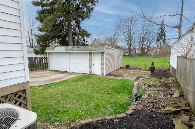 view of yard with central air condition unit, fence, an outbuilding, and a detached garage