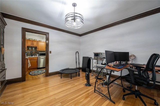 office space featuring light wood-type flooring, a sink, baseboards, an inviting chandelier, and ornamental molding