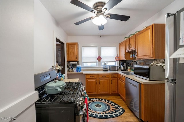 kitchen with ceiling fan, light wood-type flooring, a sink, light countertops, and stainless steel appliances