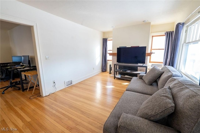 living area featuring baseboards, visible vents, and light wood-style floors