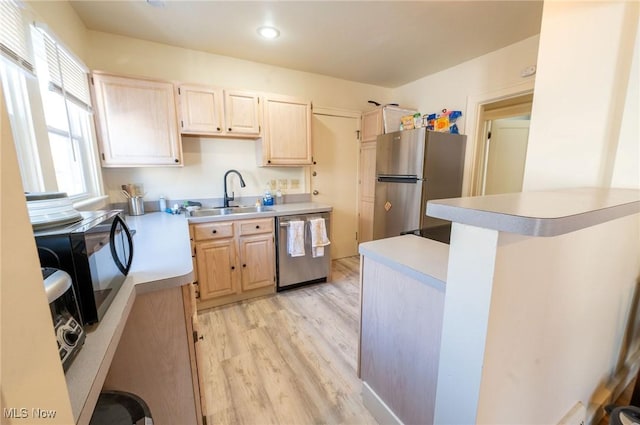 kitchen with light brown cabinets, light wood-style floors, light countertops, a sink, and appliances with stainless steel finishes