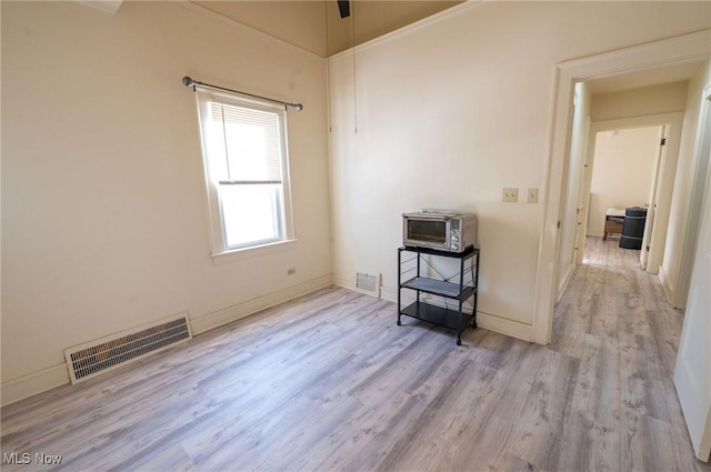 empty room with a toaster, baseboards, wood finished floors, and visible vents